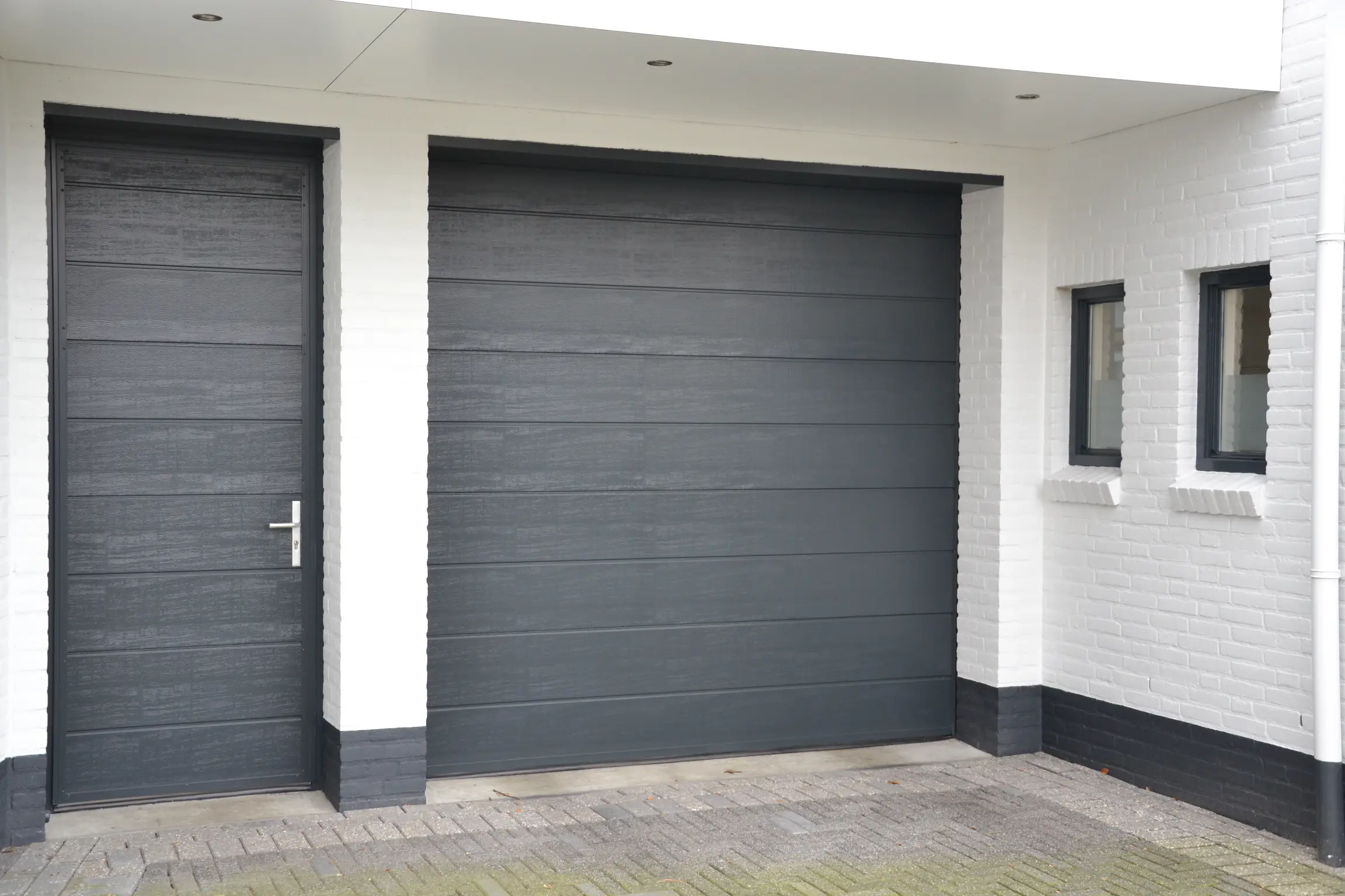 Grijze houten garagedeur met losse loopdeur